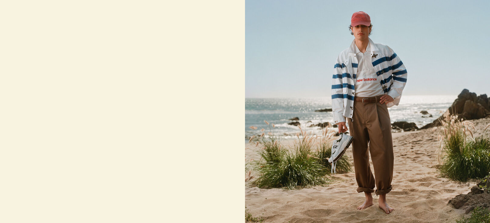 A man standing on a beach holding a pair of shoes. 