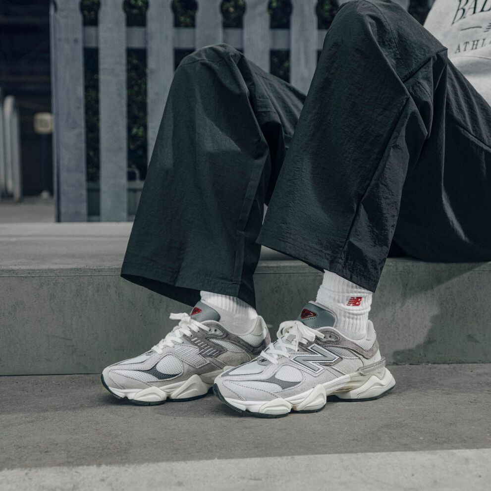 A person sitting wearing grey New Balance 9060's